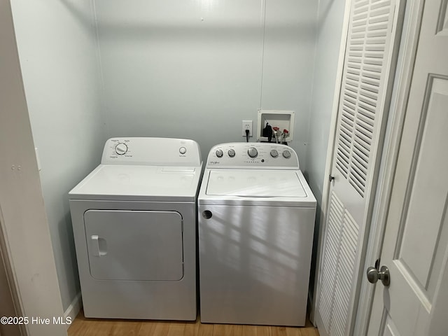 clothes washing area with washing machine and clothes dryer and light hardwood / wood-style floors