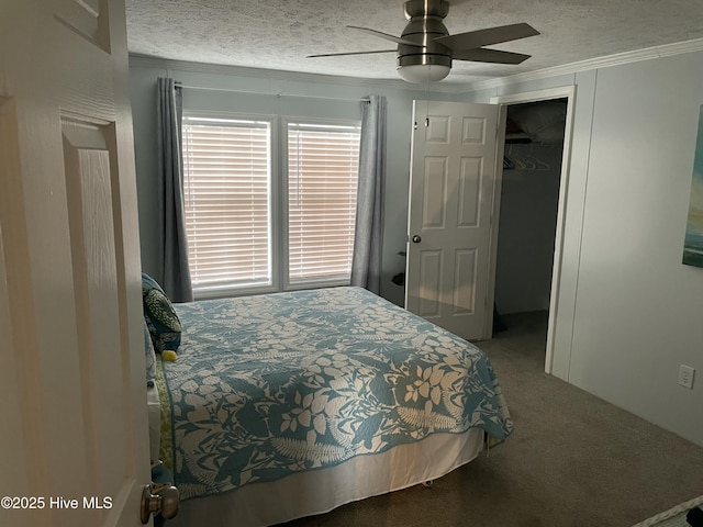 carpeted bedroom featuring a textured ceiling, ceiling fan, crown molding, a spacious closet, and a closet