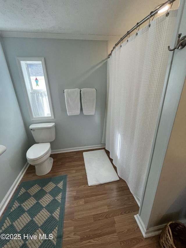 bathroom with a shower with shower curtain, toilet, wood-type flooring, and a textured ceiling