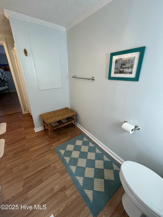 bathroom featuring toilet, ornamental molding, and hardwood / wood-style flooring