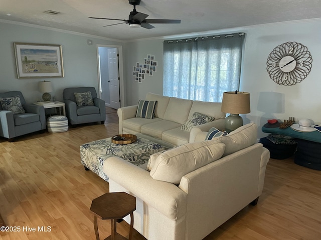 living room with a textured ceiling, light wood-type flooring, ceiling fan, and ornamental molding