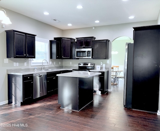 kitchen featuring a center island, sink, light stone countertops, appliances with stainless steel finishes, and dark hardwood / wood-style flooring