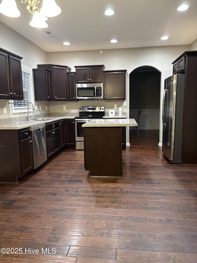 kitchen with dark hardwood / wood-style flooring, dark brown cabinets, stainless steel appliances, sink, and a kitchen island