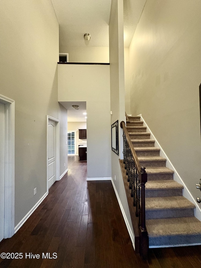 stairway with wood-type flooring and a high ceiling