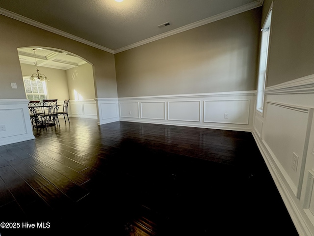 empty room featuring coffered ceiling, a textured ceiling, crown molding, an inviting chandelier, and hardwood / wood-style floors