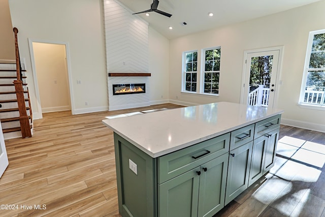 kitchen with a fireplace, lofted ceiling, light wood-style floors, open floor plan, and green cabinetry