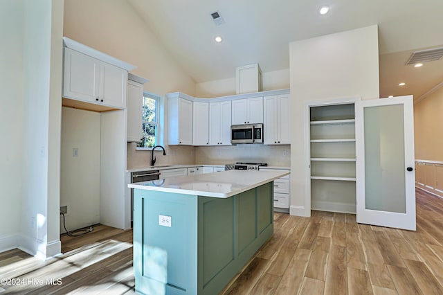 kitchen featuring visible vents, light wood-style floors, white cabinets, light countertops, and stainless steel microwave