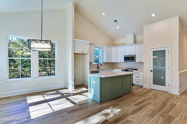 kitchen with sink, green cabinetry, white cabinets, a center island, and light hardwood / wood-style floors