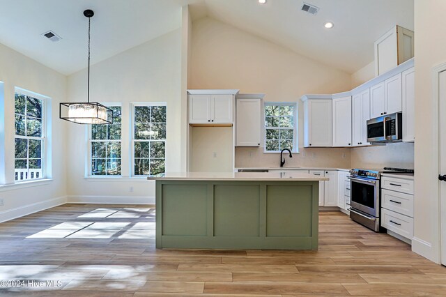 kitchen with a center island, a high ceiling, white cabinets, green cabinets, and light wood-type flooring