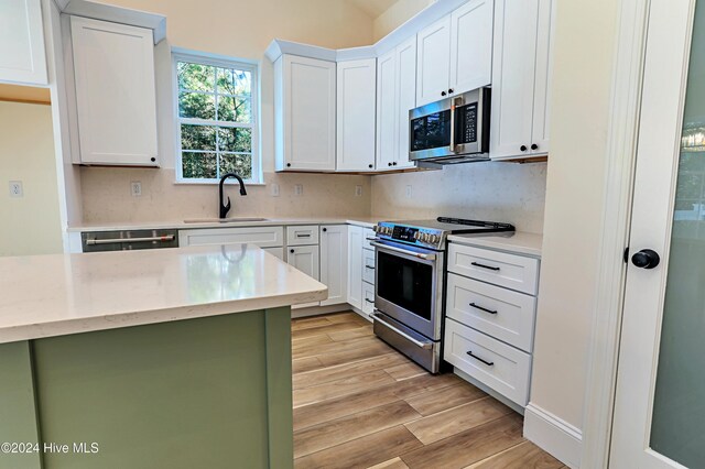 kitchen with sink, an inviting chandelier, high vaulted ceiling, white cabinets, and a center island