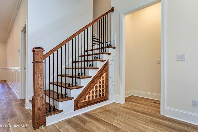 stairway with crown molding, baseboards, and wood finished floors