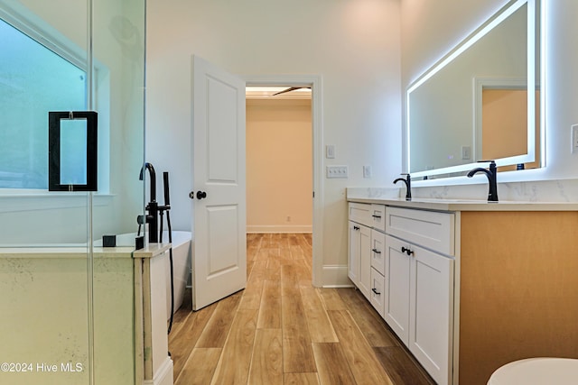 bathroom with a soaking tub, vanity, baseboards, and wood finished floors