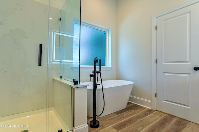 full bathroom with a stall shower, baseboards, wood finished floors, and a soaking tub