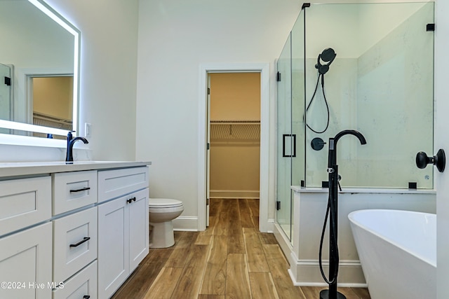 bathroom with wood finished floors, vanity, a soaking tub, a stall shower, and a walk in closet