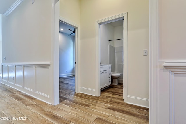 hall with ornamental molding, light wood-type flooring, and baseboards