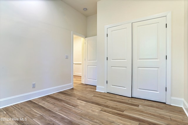 unfurnished bedroom with light wood-type flooring and a closet