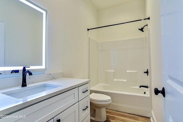 bathroom with vanity, bathing tub / shower combination, wood finished floors, and toilet