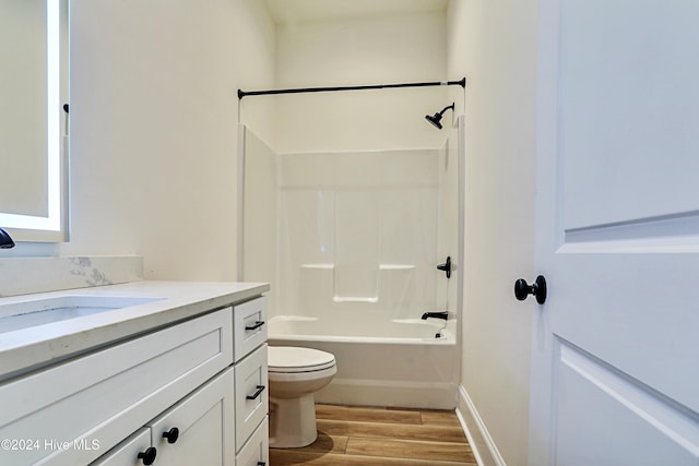 bathroom featuring baseboards, toilet, wood finished floors, bathtub / shower combination, and vanity