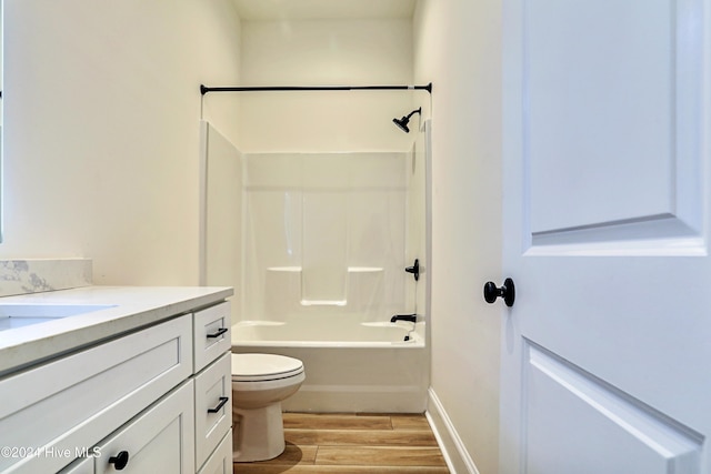 bathroom featuring toilet, wood finished floors, vanity, baseboards, and tub / shower combination