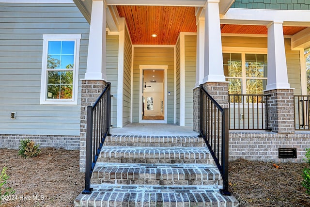 property entrance featuring covered porch, brick siding, and crawl space