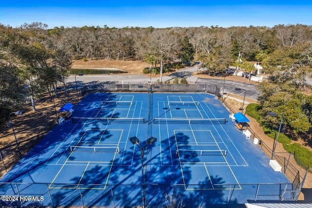 view of sport court featuring fence and a view of trees