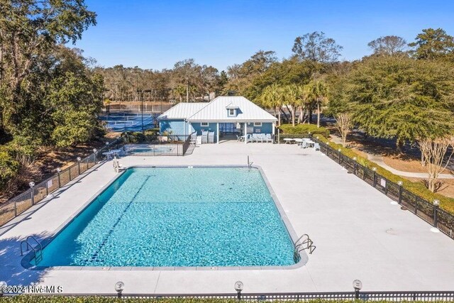 community pool with a patio area and fence