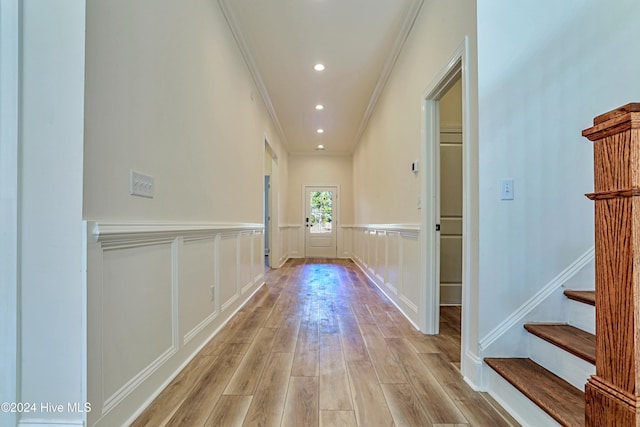 hall featuring light wood-style flooring, recessed lighting, a wainscoted wall, a decorative wall, and ornamental molding