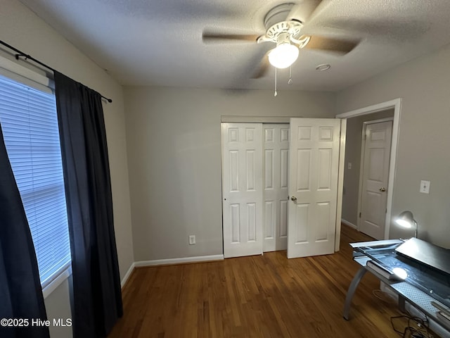 unfurnished office with ceiling fan, dark hardwood / wood-style flooring, and a textured ceiling