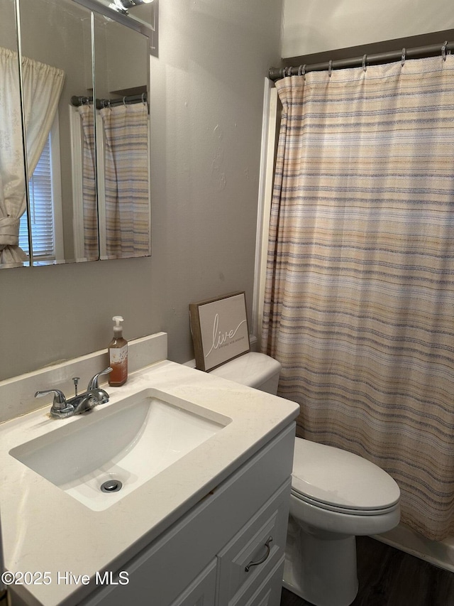 bathroom featuring vanity, toilet, and walk in shower