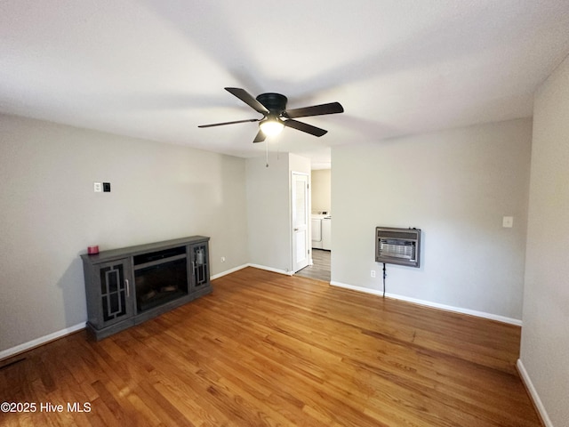 unfurnished living room with ceiling fan, washer / dryer, wood-type flooring, and heating unit