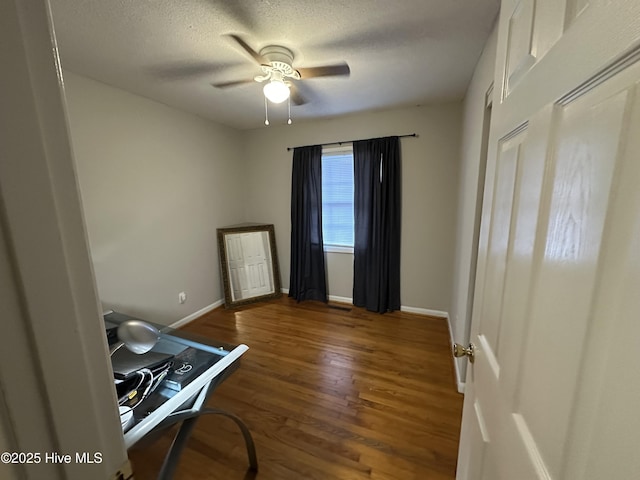 interior space with a textured ceiling, ceiling fan, and dark wood-type flooring