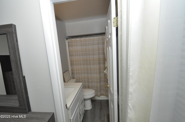 bathroom with hardwood / wood-style floors, vanity, toilet, and walk in shower