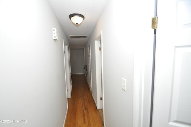 corridor with a textured ceiling and dark hardwood / wood-style floors