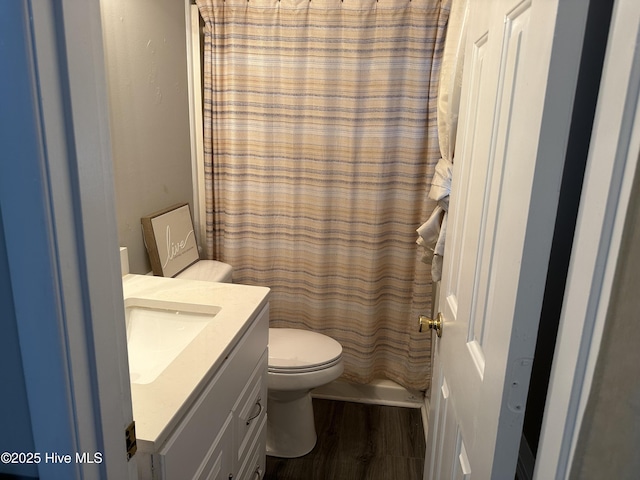 full bathroom with hardwood / wood-style floors, vanity, shower / tub combo, and toilet