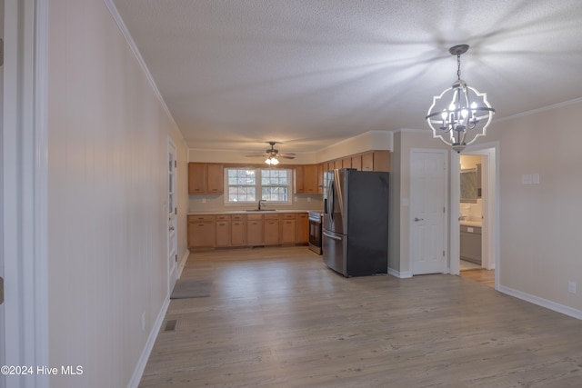 kitchen featuring light hardwood / wood-style floors, pendant lighting, appliances with stainless steel finishes, ceiling fan with notable chandelier, and ornamental molding