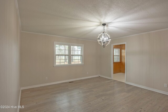 kitchen with decorative light fixtures, black fridge, ornamental molding, and light wood-type flooring