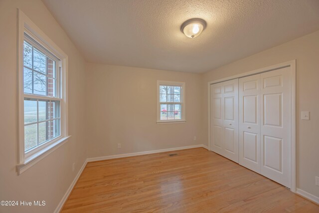 unfurnished bedroom with a textured ceiling, connected bathroom, light hardwood / wood-style floors, and sink