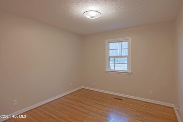 unfurnished bedroom with a textured ceiling, light hardwood / wood-style flooring, and a closet