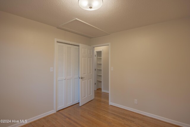 unfurnished room with a textured ceiling and light hardwood / wood-style flooring