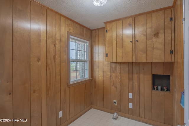 clothes washing area featuring wooden walls, hookup for a washing machine, a textured ceiling, and hookup for an electric dryer