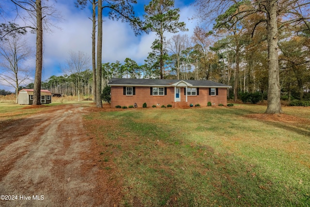 ranch-style house featuring a front yard and a storage shed