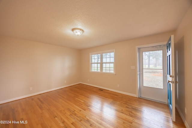 unfurnished room featuring light hardwood / wood-style floors and a textured ceiling