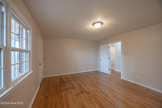 spare room featuring light wood-type flooring and a textured ceiling