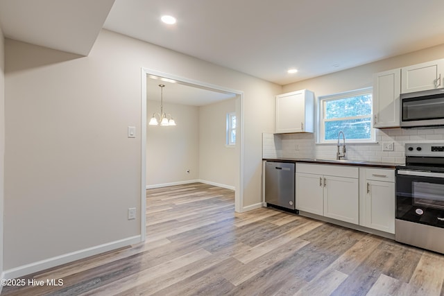 kitchen with white cabinetry, sink, an inviting chandelier, appliances with stainless steel finishes, and light wood-type flooring