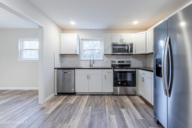 kitchen featuring a wealth of natural light, stainless steel appliances, sink, light hardwood / wood-style flooring, and white cabinetry