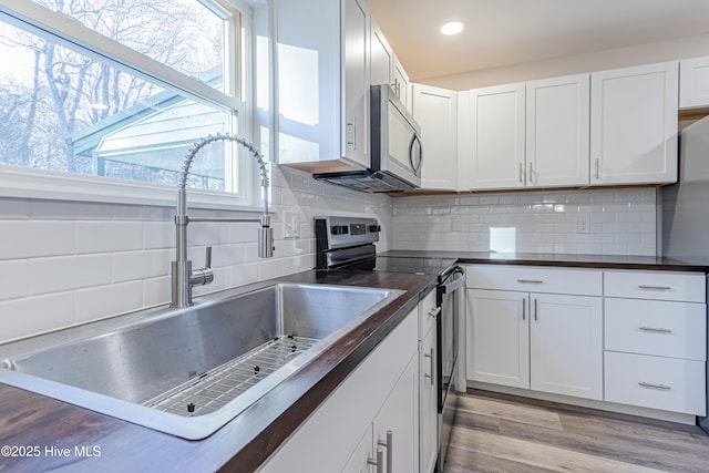 kitchen with wood counters, white cabinetry, sink, and appliances with stainless steel finishes