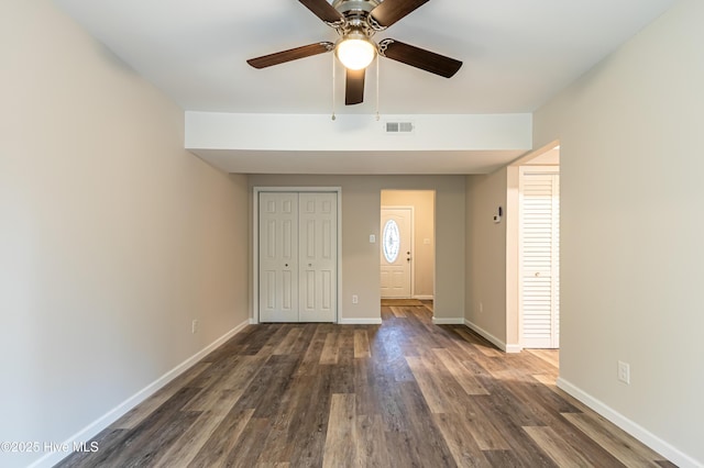 unfurnished bedroom with ceiling fan, dark wood-type flooring, and a closet