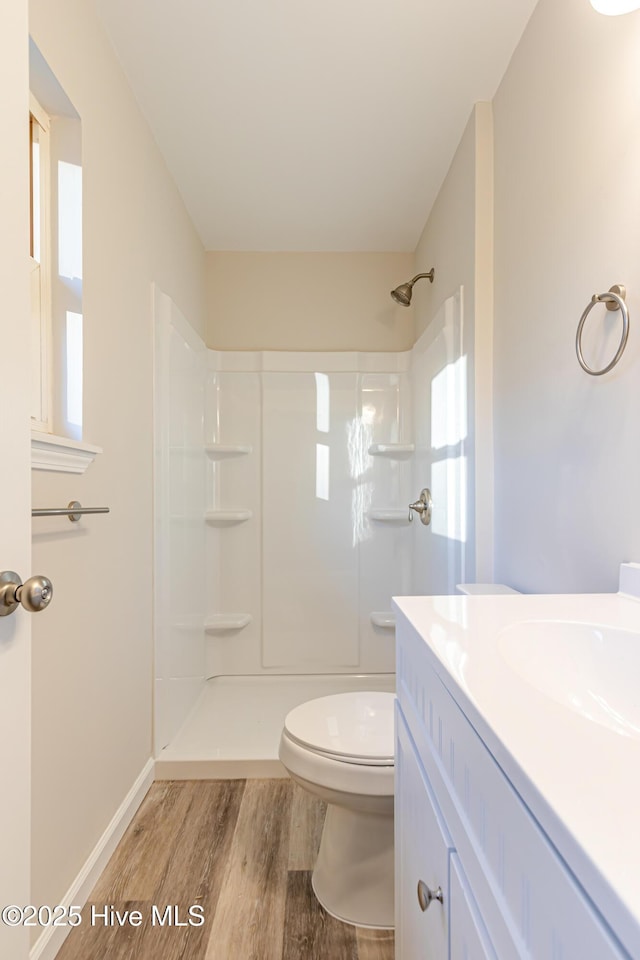 bathroom featuring a shower, toilet, vanity, and hardwood / wood-style flooring