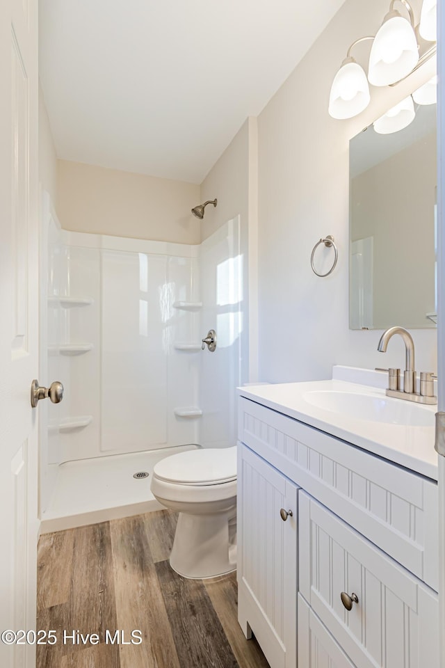 bathroom with a shower, hardwood / wood-style floors, vanity, and toilet