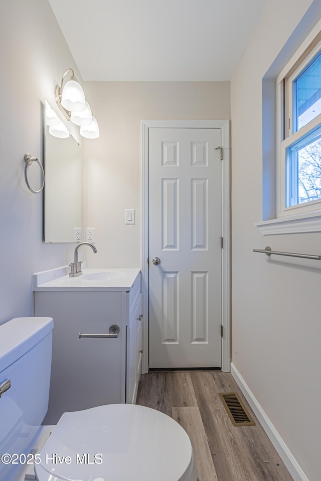 bathroom with toilet, vanity, and hardwood / wood-style flooring